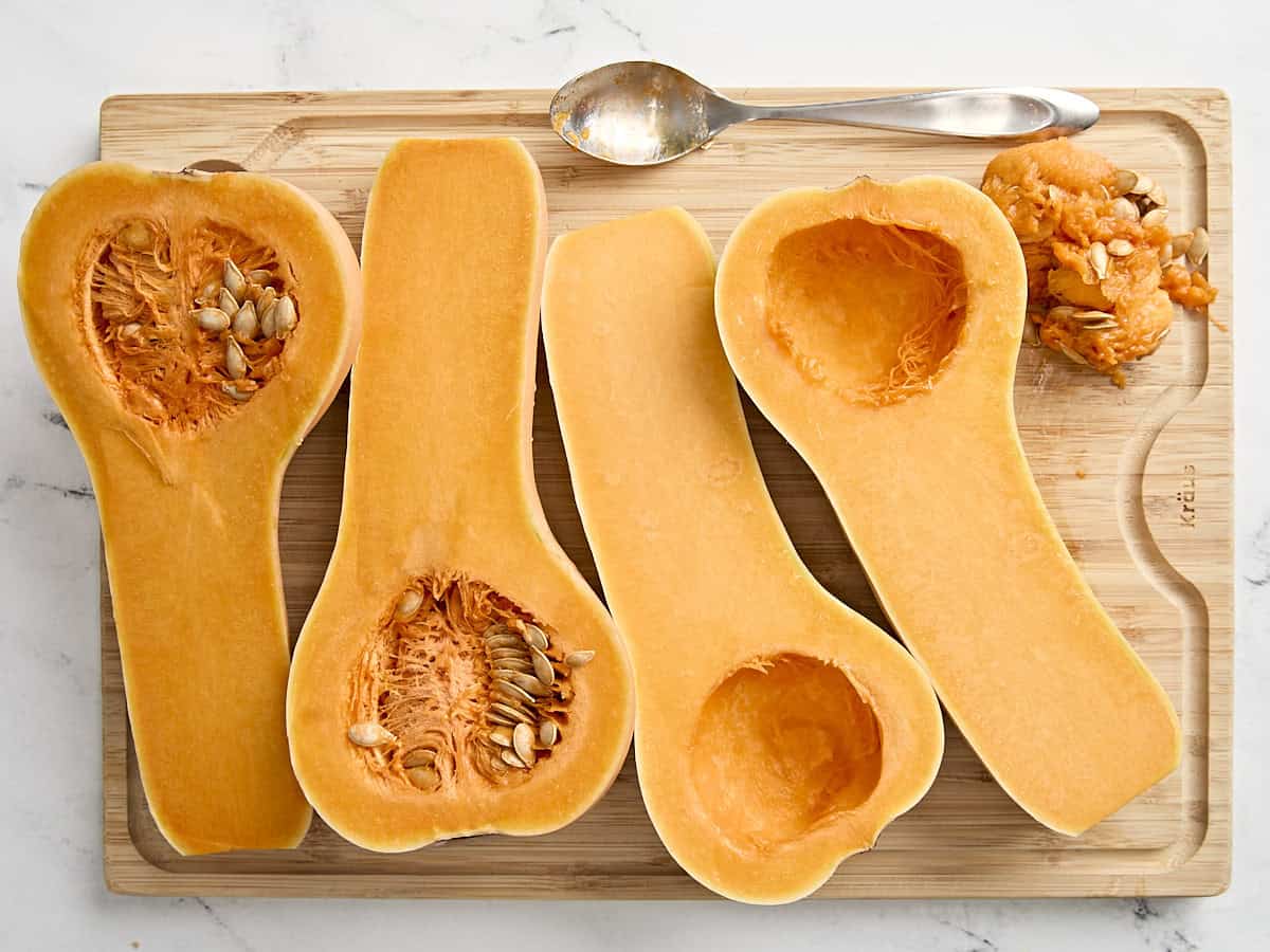 2 courges musquées coupées en deux sur une planche à découper en bois, une avec les graines enlevées.