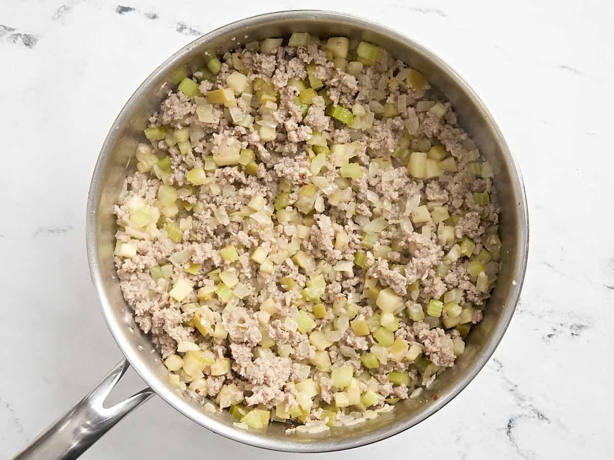 Saucisse hachée dorée et légumes dans une poêle.