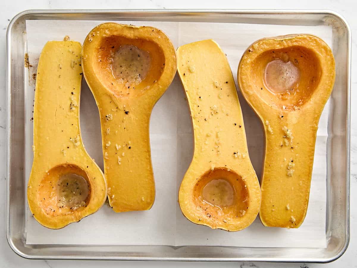 4 moitiés de courge musquée cuites au four sur une plaque à pâtisserie.