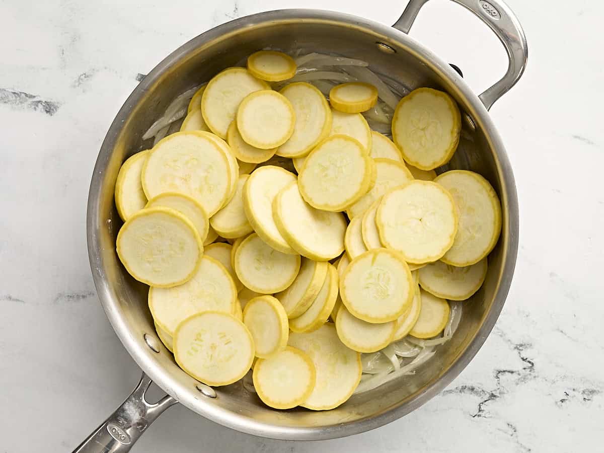 Courge jaune tranchée cuite dans une poêle avec des oignons.