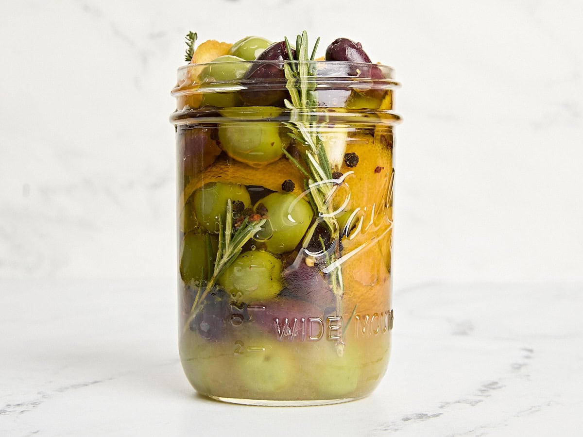 Vue latérale des olives marinées dans un pot Mason.