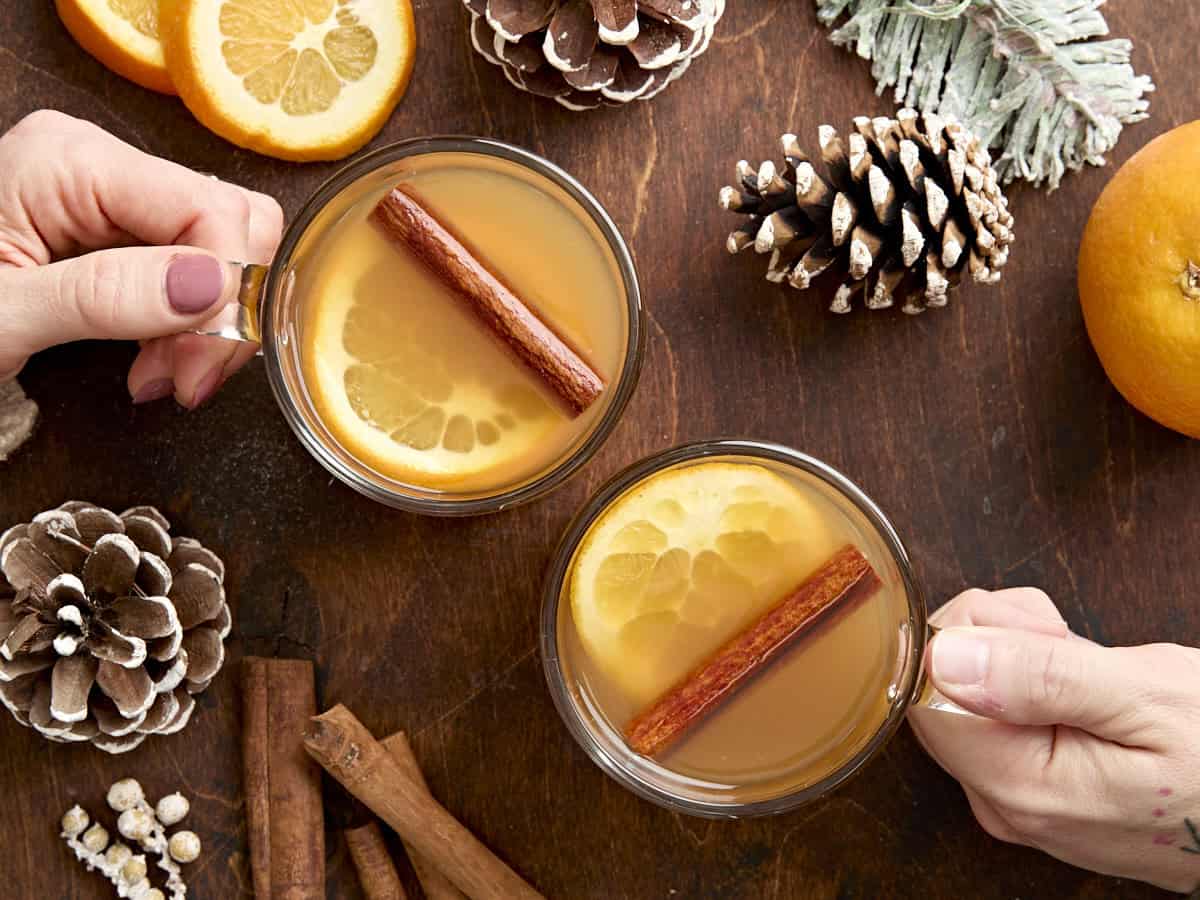 Vue aérienne de deux mains tenant une tasse de cidre de pomme chaud.