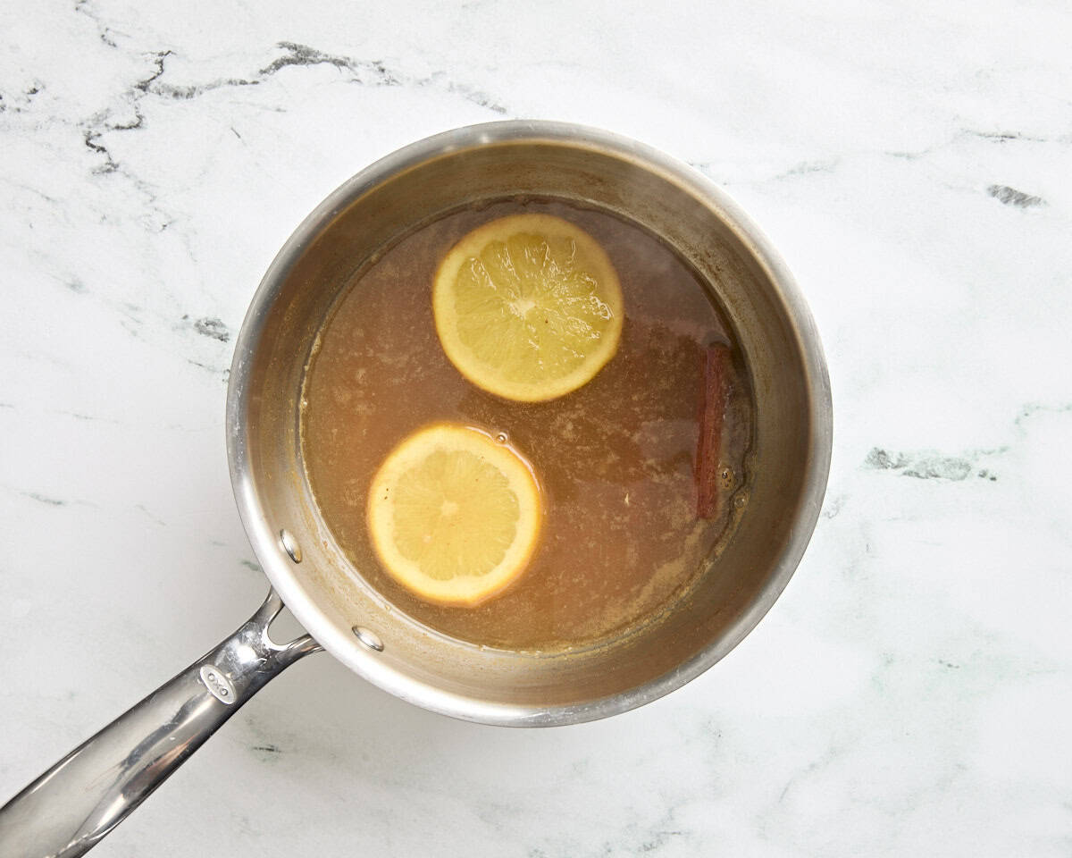 Cidre de pomme chaud dans une poêle avec des tranches d'oranges et un bâton de cannelle.