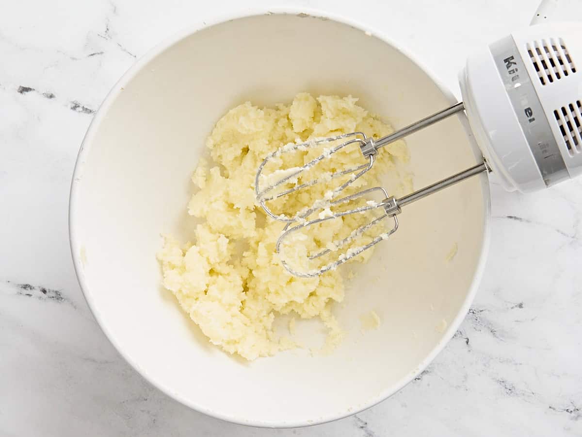 Beurre en crème et sucre dans un bol à mélanger avec un batteur à main.