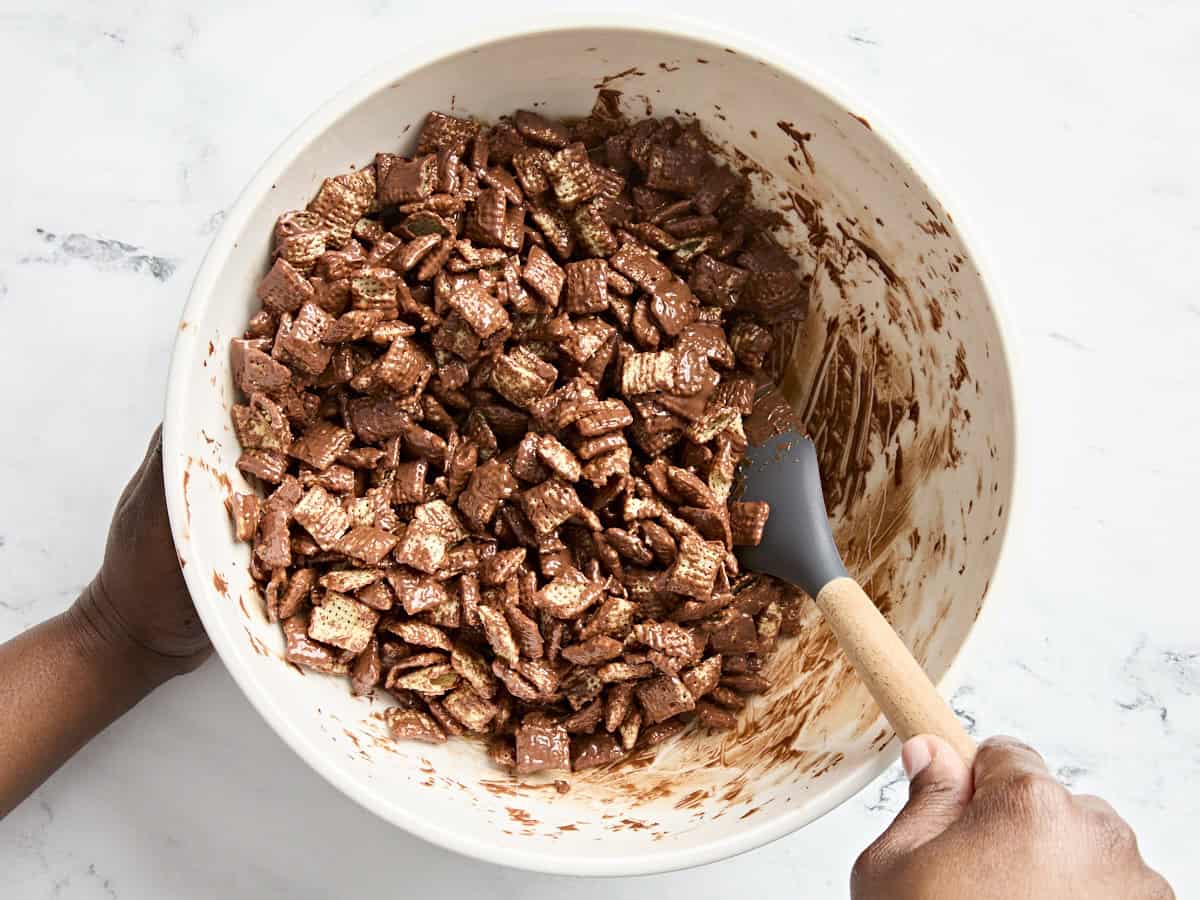 Une spatule mélangeant du chocolat fondu et des céréales de riz chex.