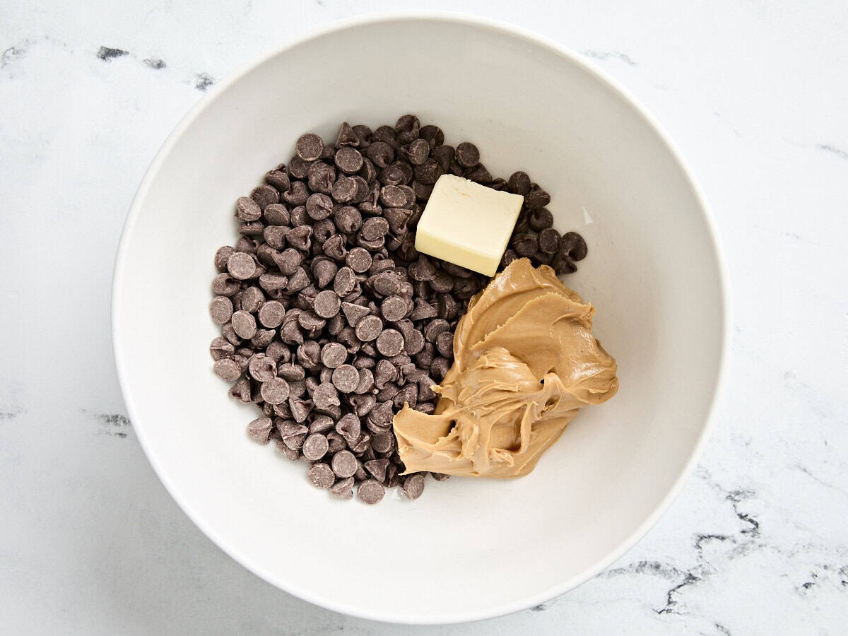 Des pépites de chocolat mi-sucré, un carré de beurre et du beurre de cacahuète dans un bol.