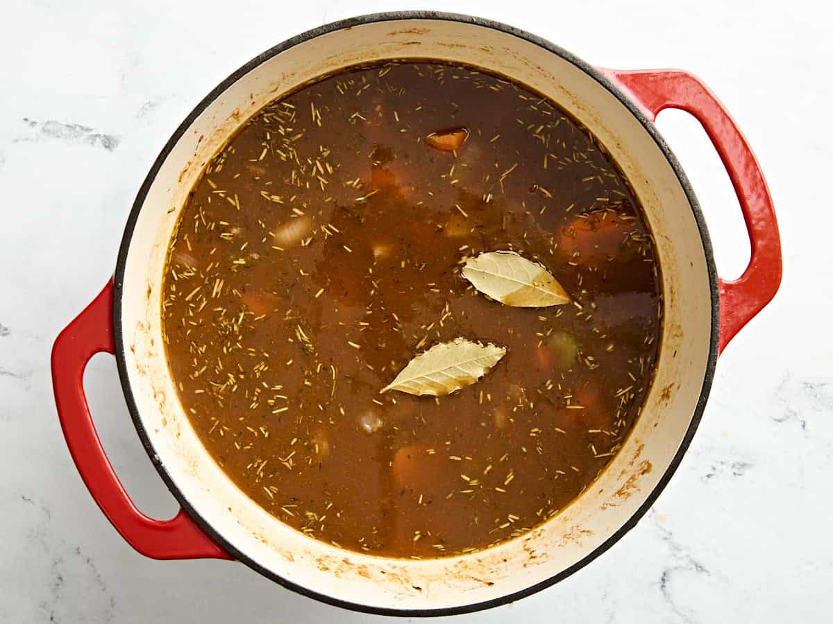 Feuilles de laurier ajoutées au ragoût de bœuf dans une cocotte.