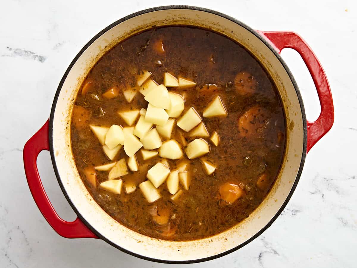 Pommes de terre ajoutées au ragoût de bœuf dans une cocotte.