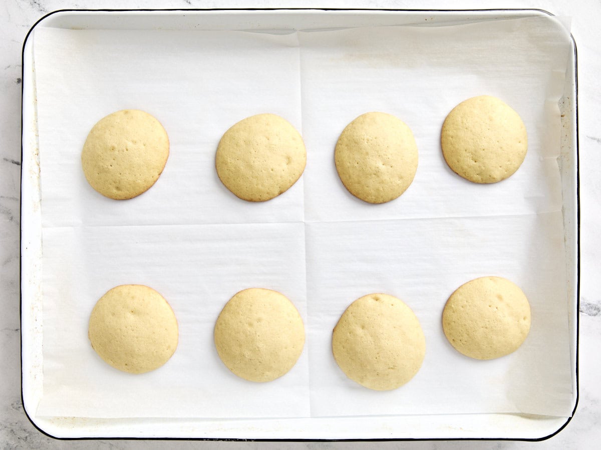 Biscuits noirs et blancs non givrés sur une plaque à pâtisserie tapissée de papier sulfurisé.