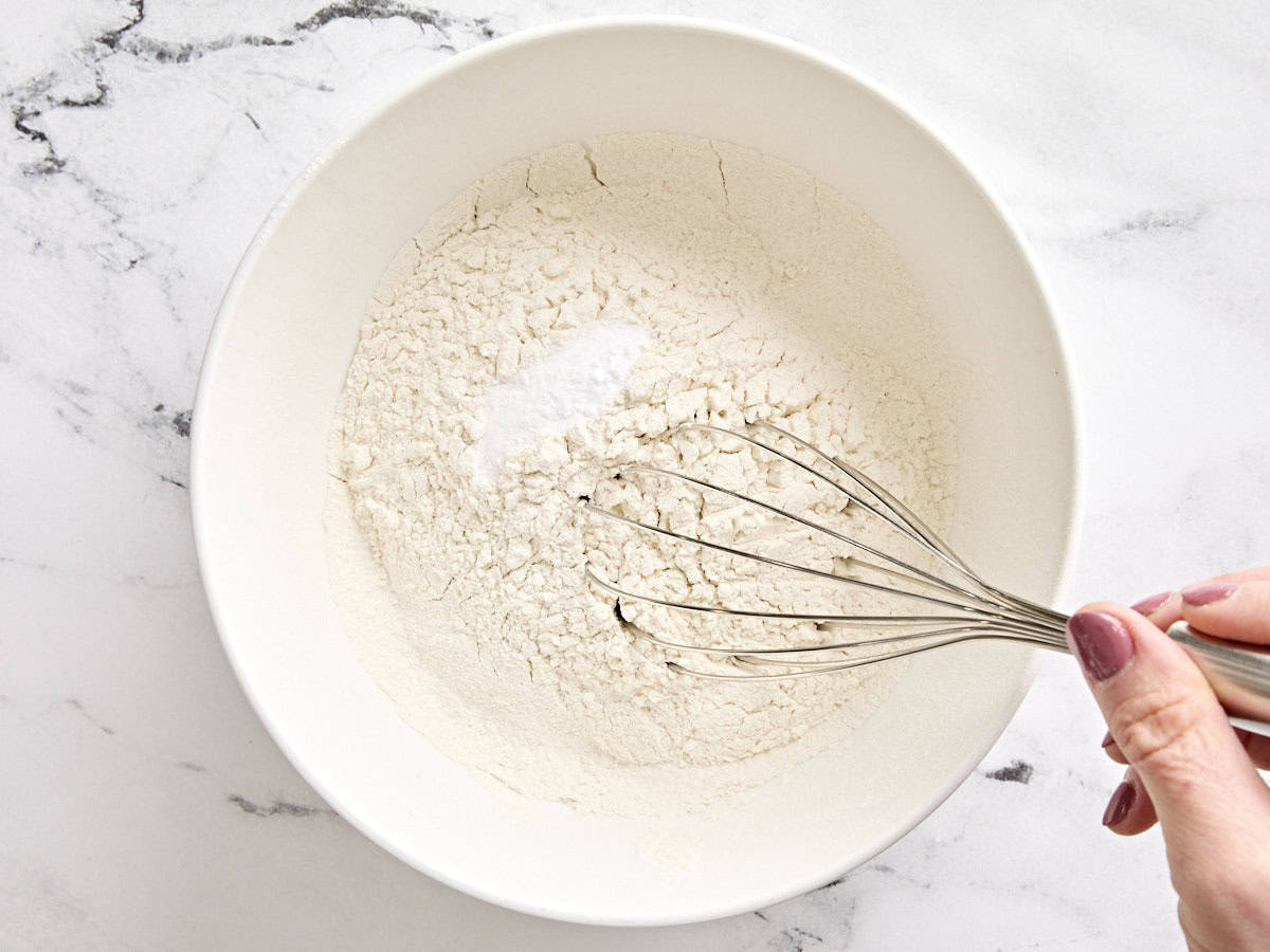 Le bicarbonate de soude et le sel sont mélangés à de la farine tamisée dans un bol.