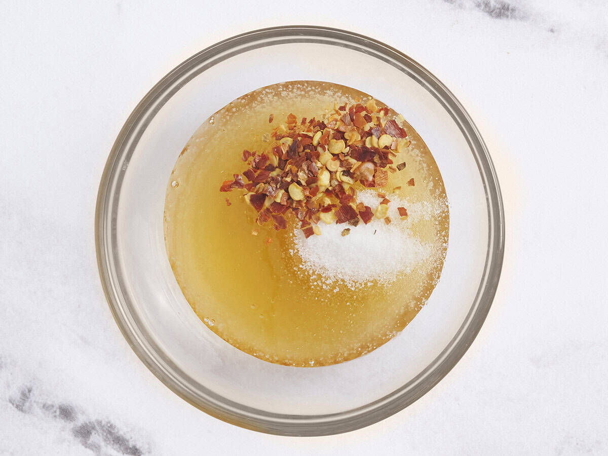 Les flocons de sel et de chili ont ajouté à un bol de miel.