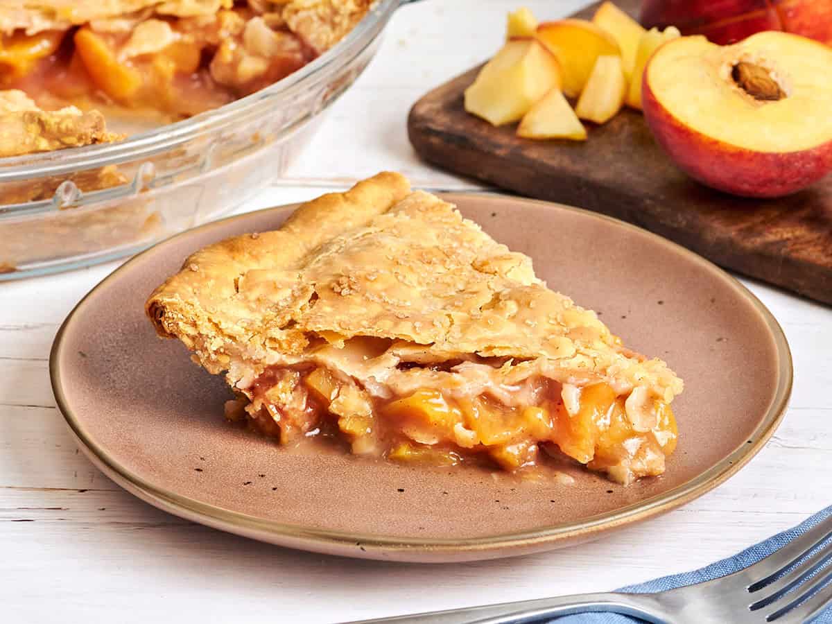 Side view of a slice of peach pie on a plate.