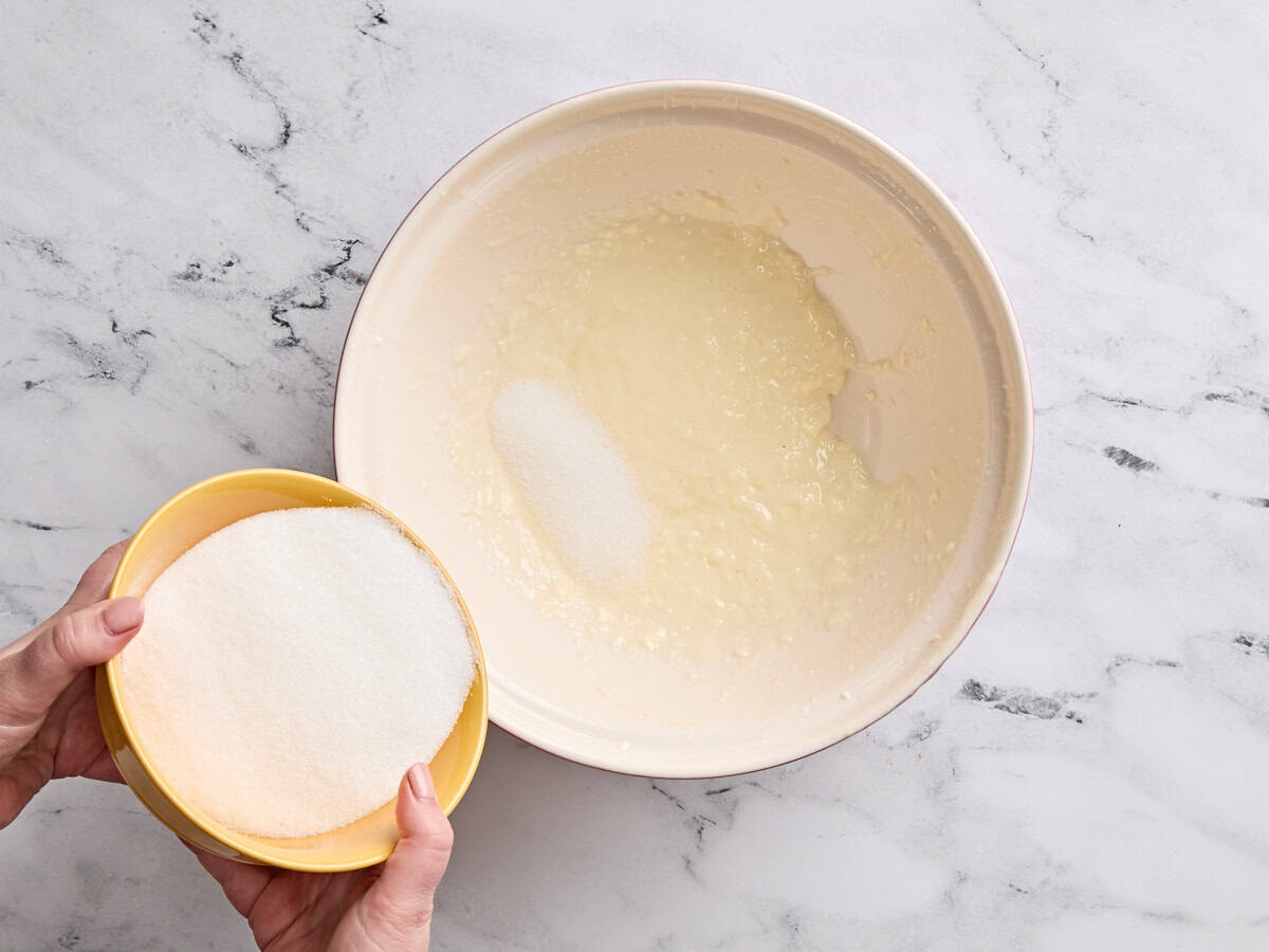 Le sucre versé dans le beurre battu et l'huile.