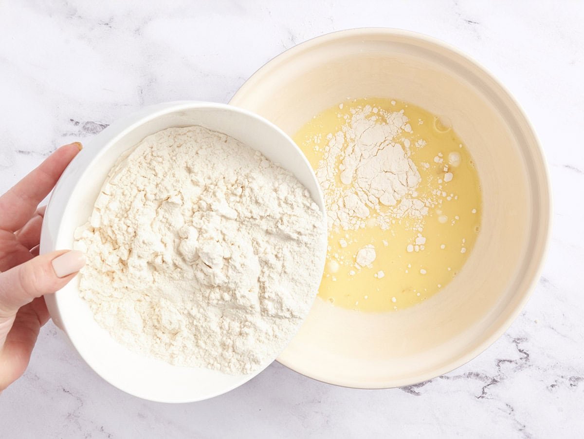 La farine versée dans un mélange d'oeufs et de lait.