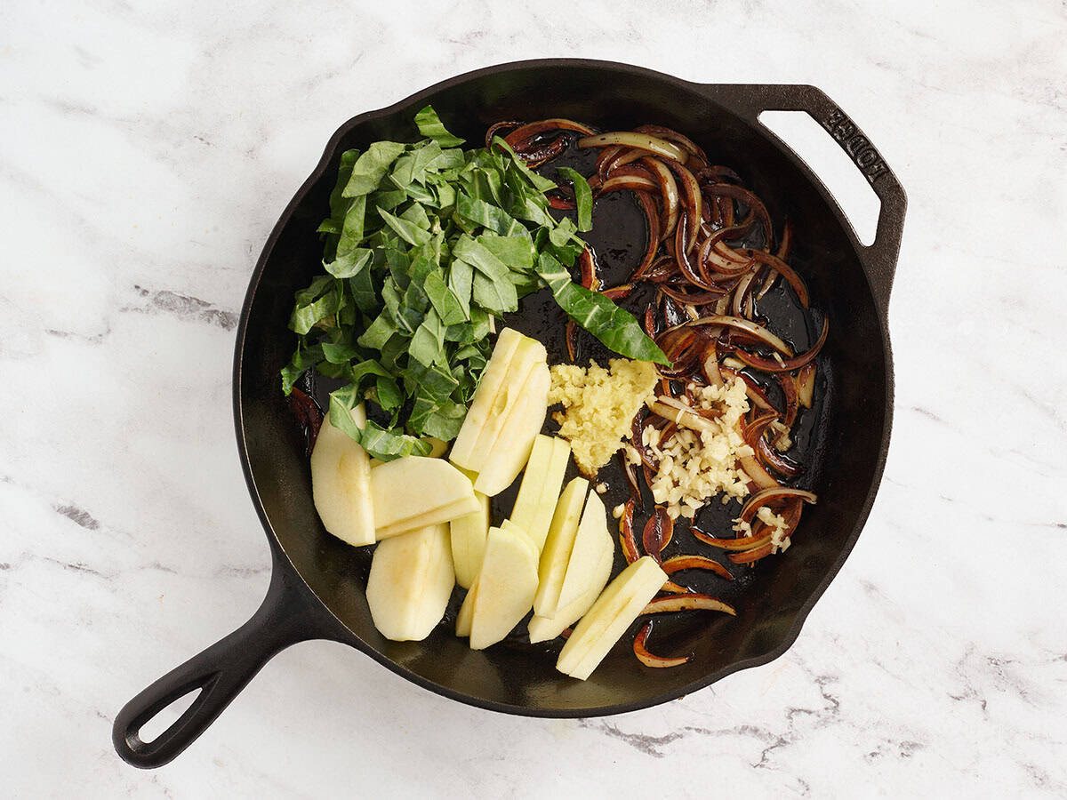 Le chou vert, la pomme tranchée, le gingembre râpé et l'ail haché ont ajouté à une poêle avec des oignons sautés.