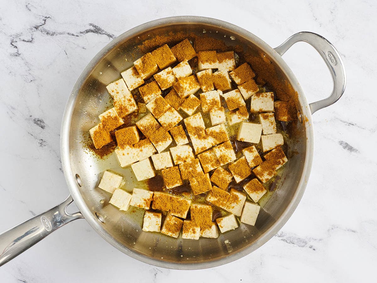 Les épices ont ajouté à une poêle avec des cubes de tofu fermes.