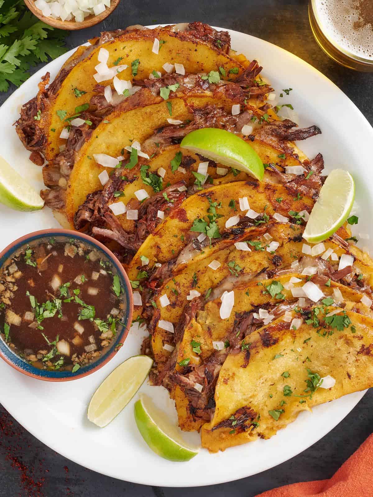 Vue aérienne des tacos de birria maison sur une assiette.