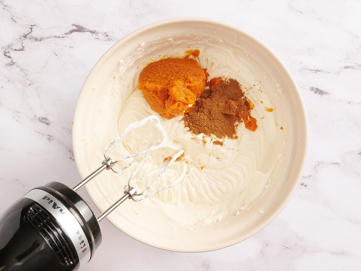 Épices de citrouille et purée de citrouille dans un bol fourré au cheesecake.