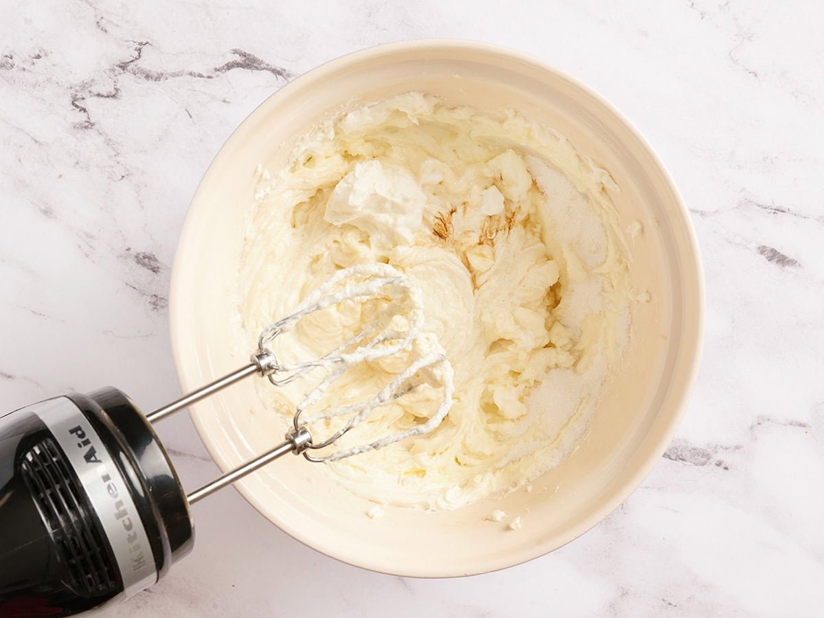 Cheesecake remplissant un bol avec un batteur à main.