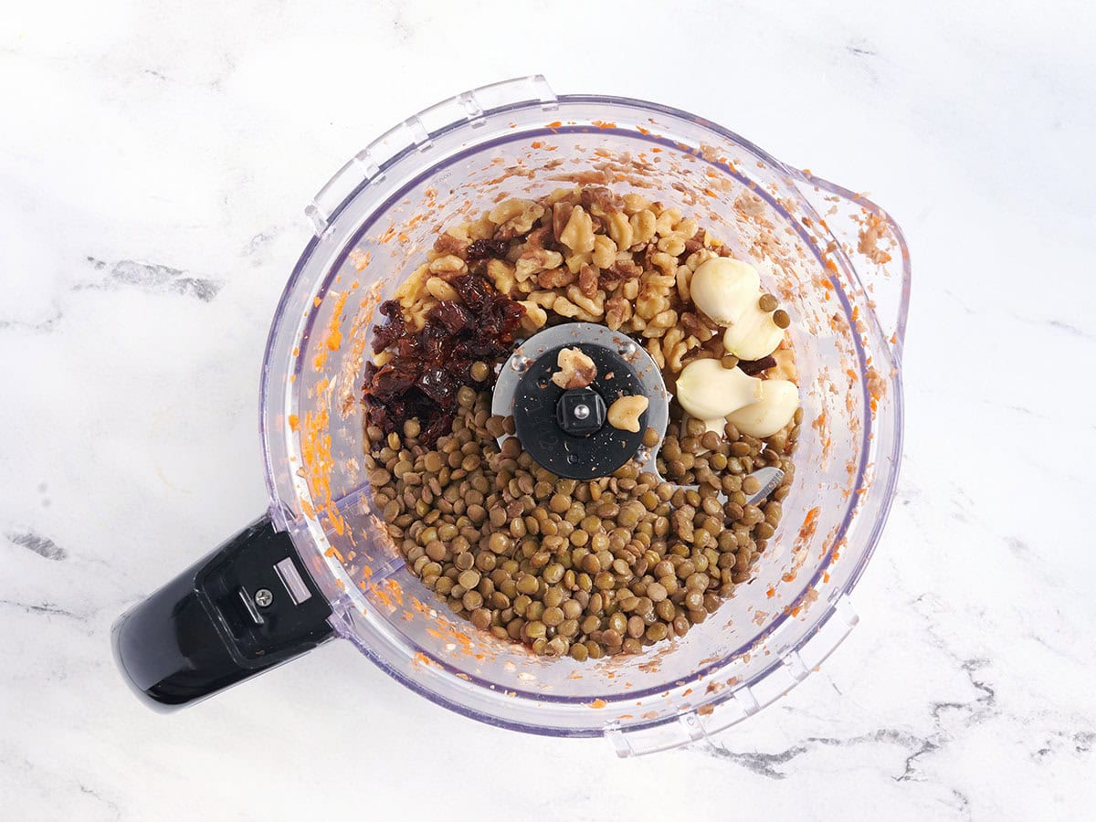 Ail, lentilles, noix et tomates séchées au soleil dans un robot culinaire.