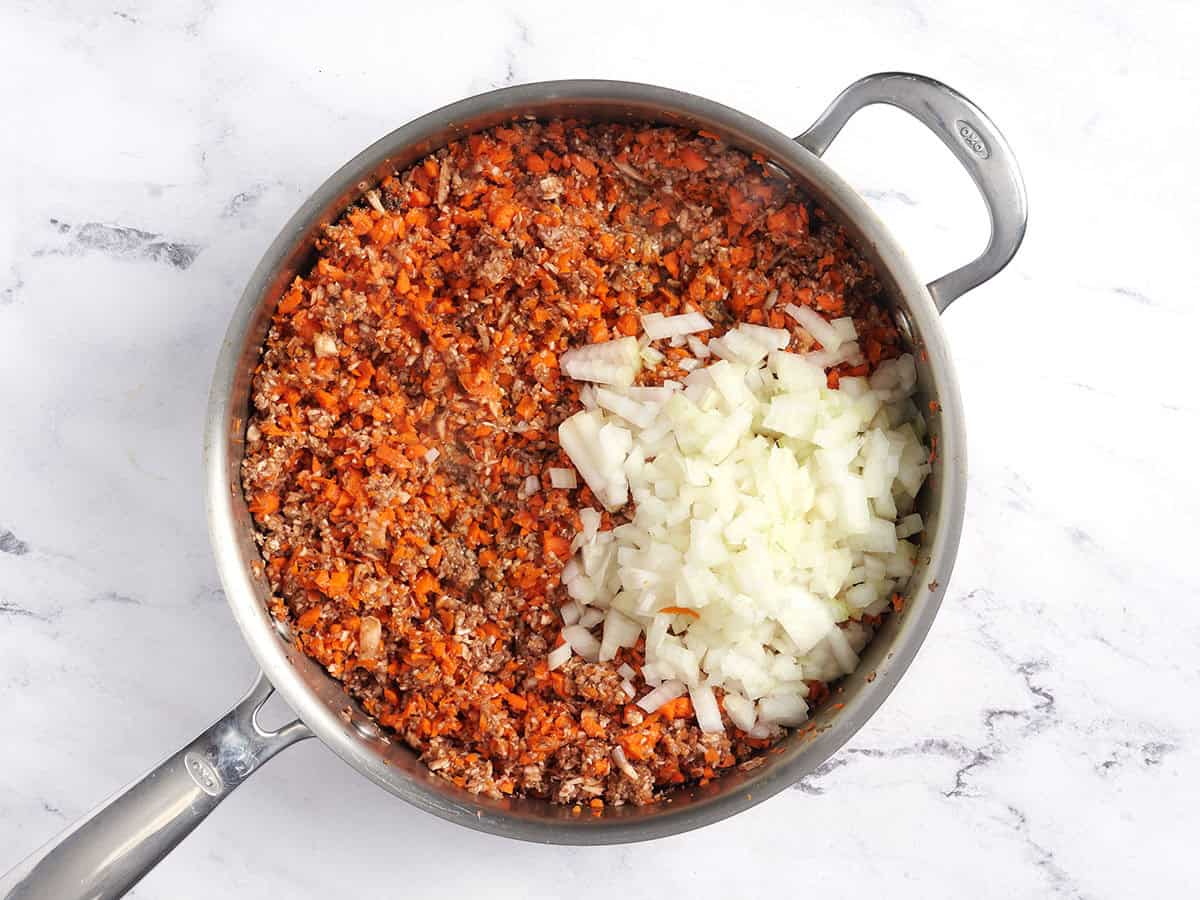Carottes, champignons et oignons transformés dans une casserole.
