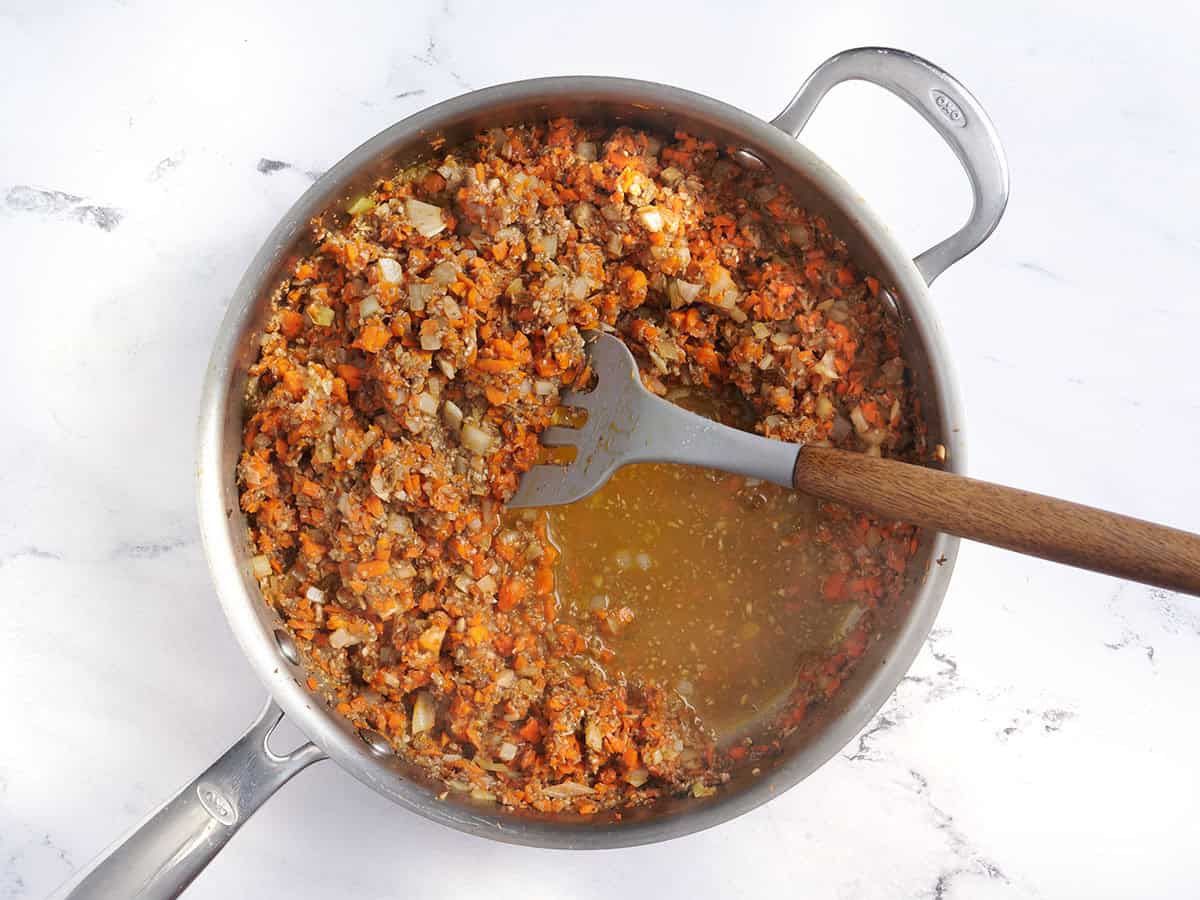 Ingrédients du pain de viande aux lentilles dans une sauteuse avec une spatule.