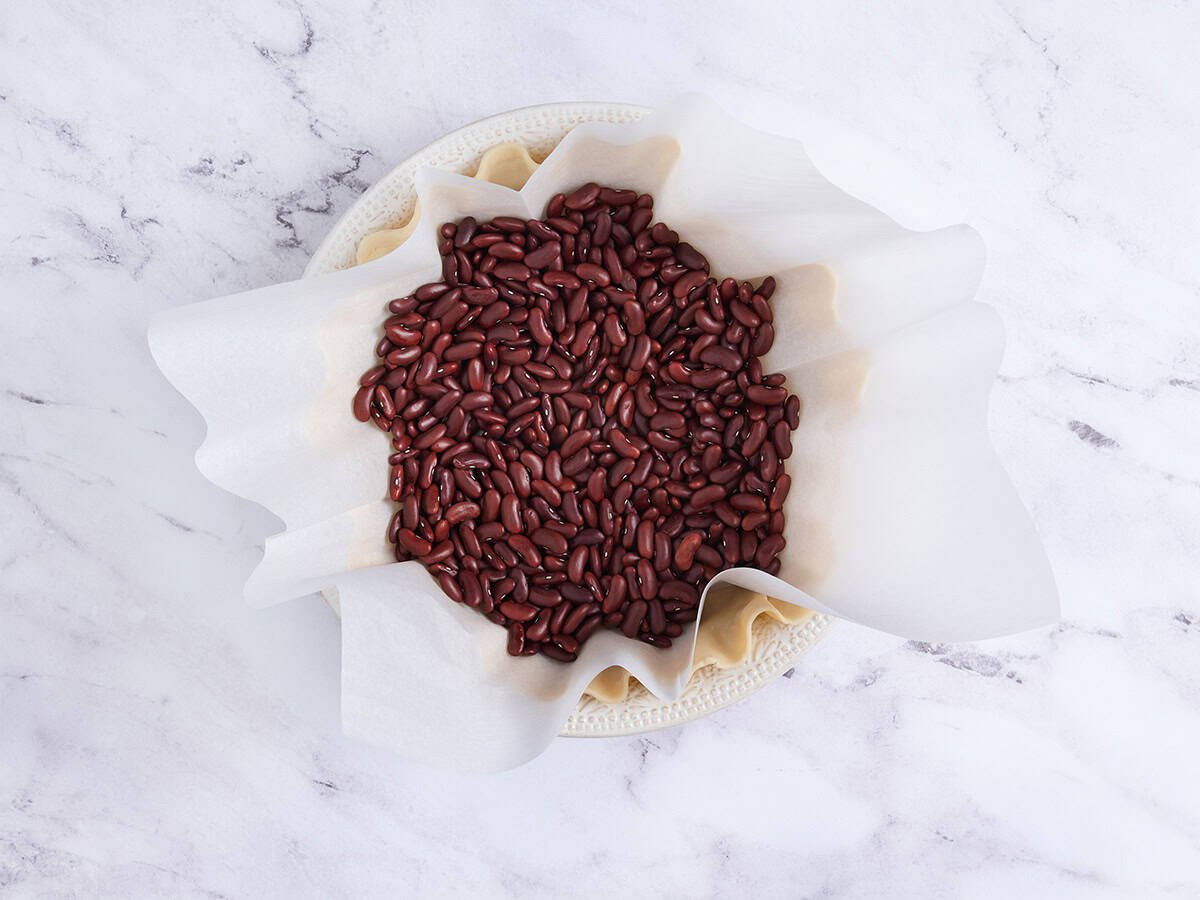 Haricots secs en parchemin sur un fond de tarte pour cuisson à l'aveugle.