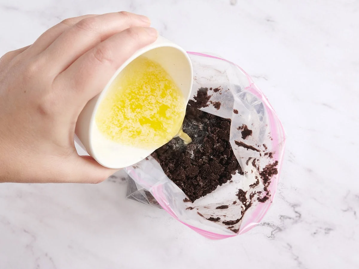 Le beurre est versé dans un sac ziplock rempli de miettes de biscuits.