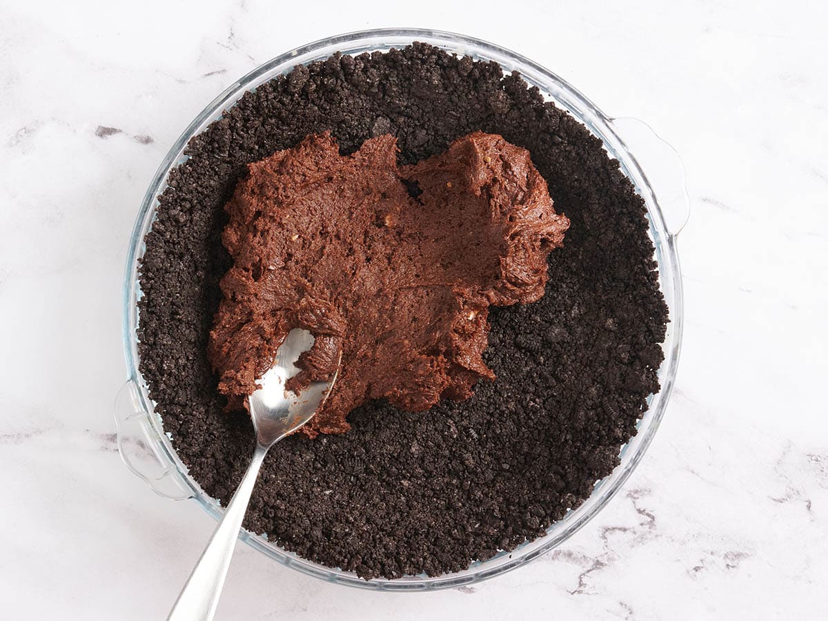 Pâte à brownie étalée sur une croûte à tarte au chocolat.
