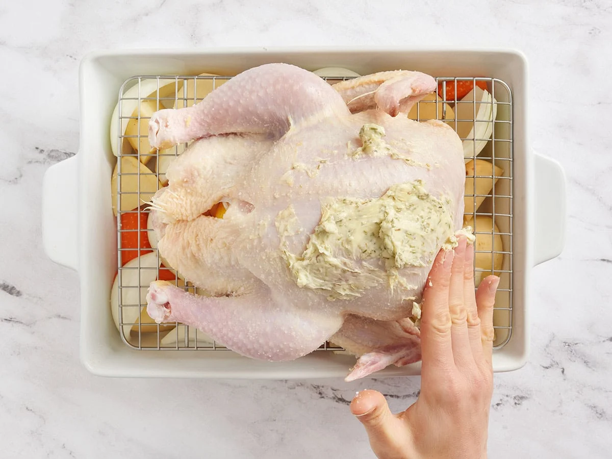 Un poulet entier frotté avec du beurre assaisonné.
