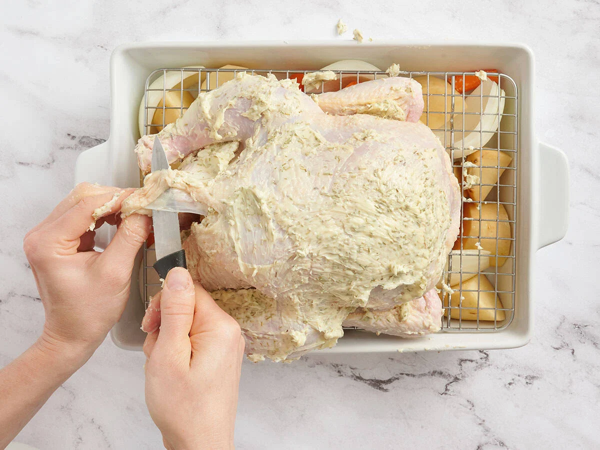 Un couteau perçant la peau d'un poulet entier.