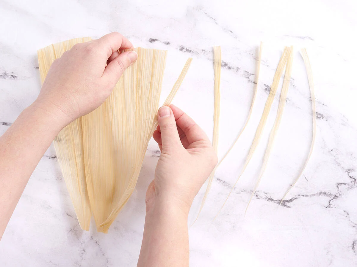 Mains déchiquetant une balle de maïs.