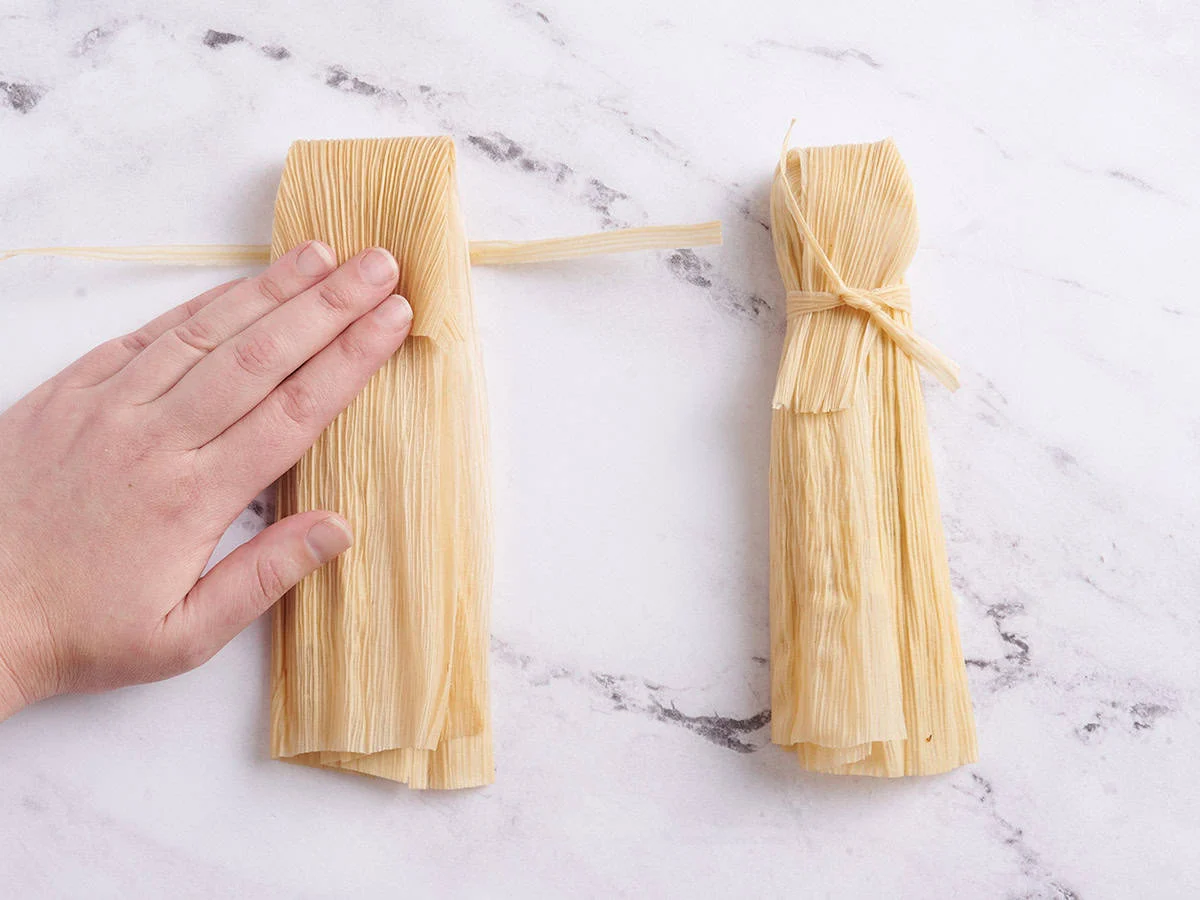 Mains pliant un tamale.