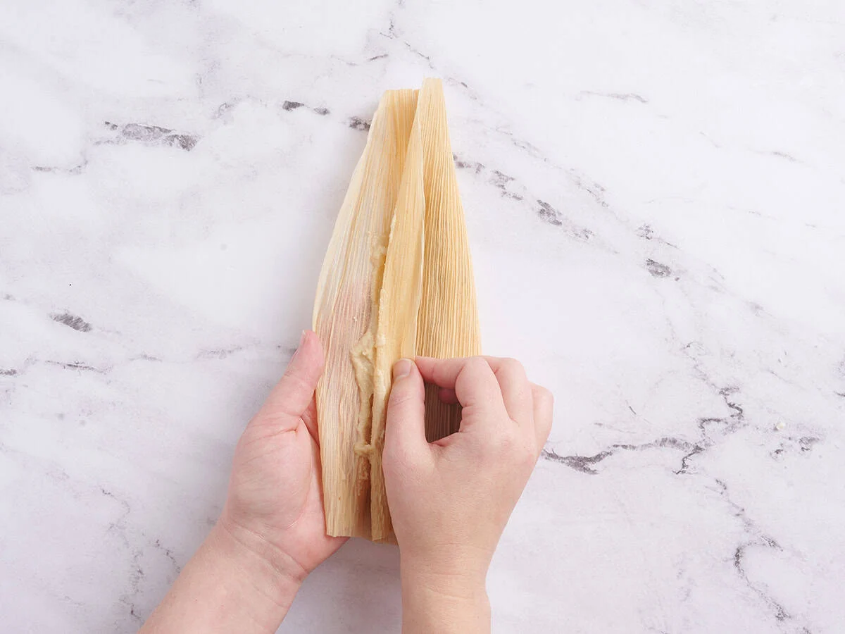 Mains repliant le côté d'une balle de maïs sur la garniture.