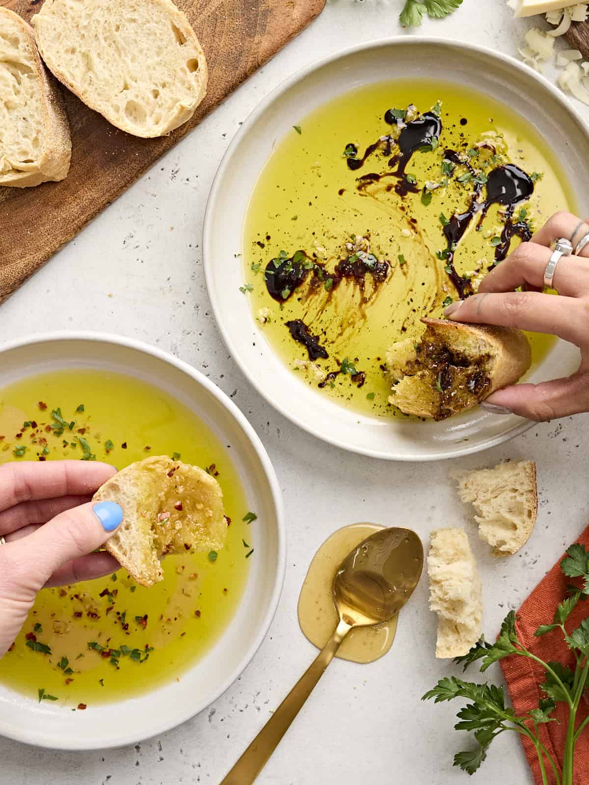 Trempette chaude au miel et trempette balsamique dans des bols blancs sur un plateau blanc avec du pain et une cuillère. 