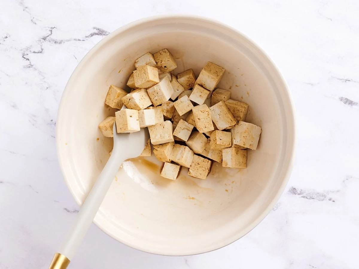 Cubes de tofu mélangés à de la sauce soja dans un bol blanc.