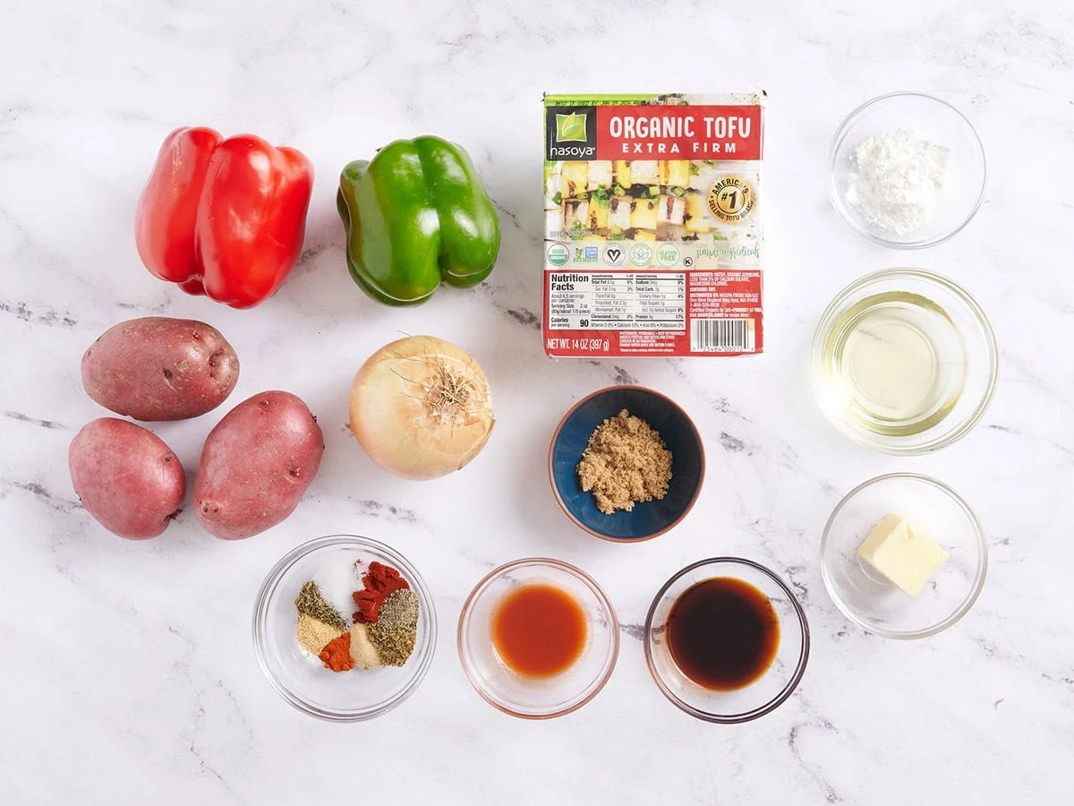 Ingrédients pour préparer du tofu cajun et des légumes sur une plaque à pâtisserie. 