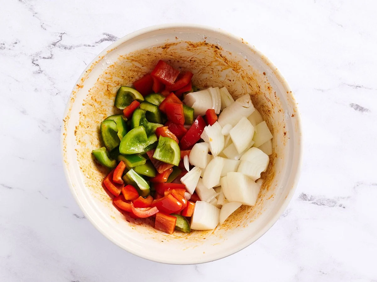 Poivrons et oignons dans un bol blanc avec l'assaisonnement cajun. 