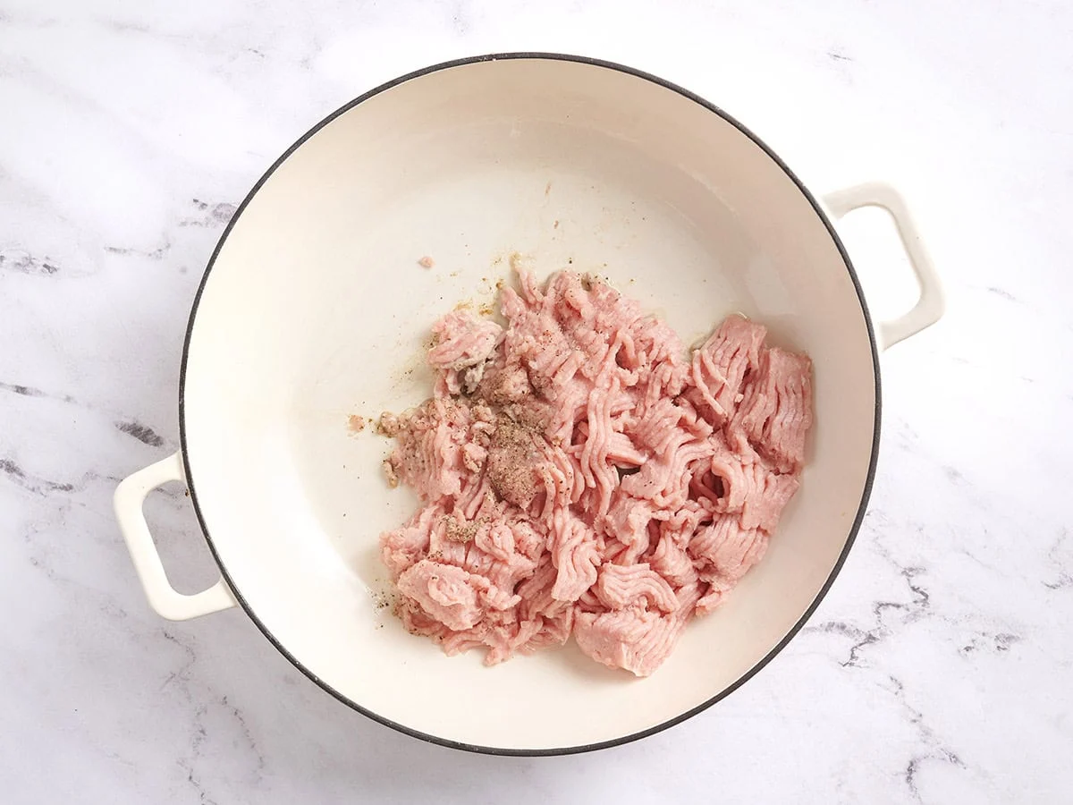 Dinde hachée assaisonnée de sel et de poivre dans une poêle. 