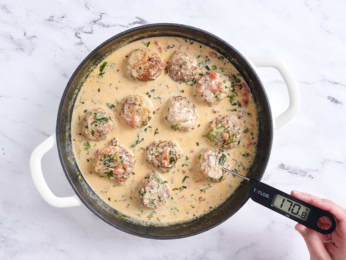 Un thermomètre vérifiant la température interne des boulettes de viande 