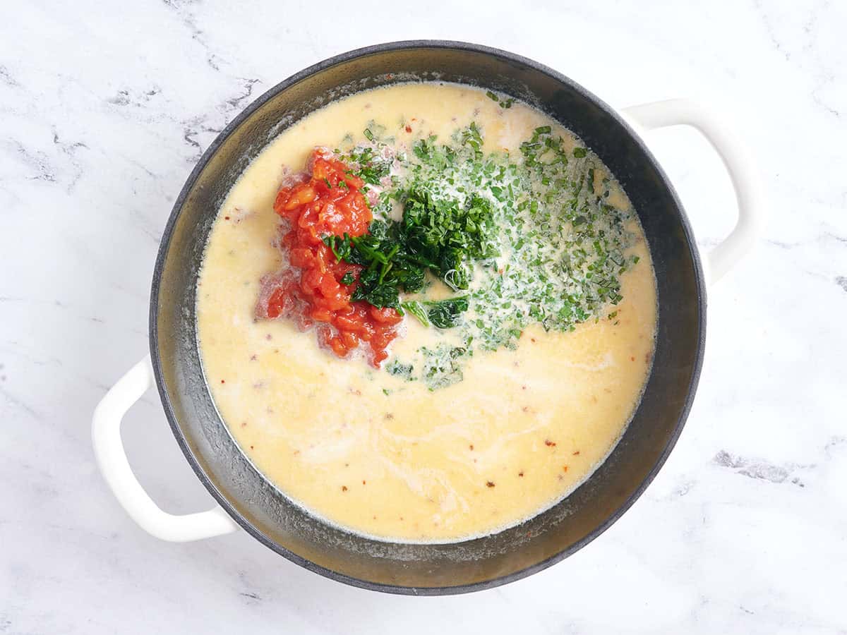 Tomates, épinards, herbes et parme ajoutés à la sauce pour m'épouser des boulettes de viande dans une poêle.