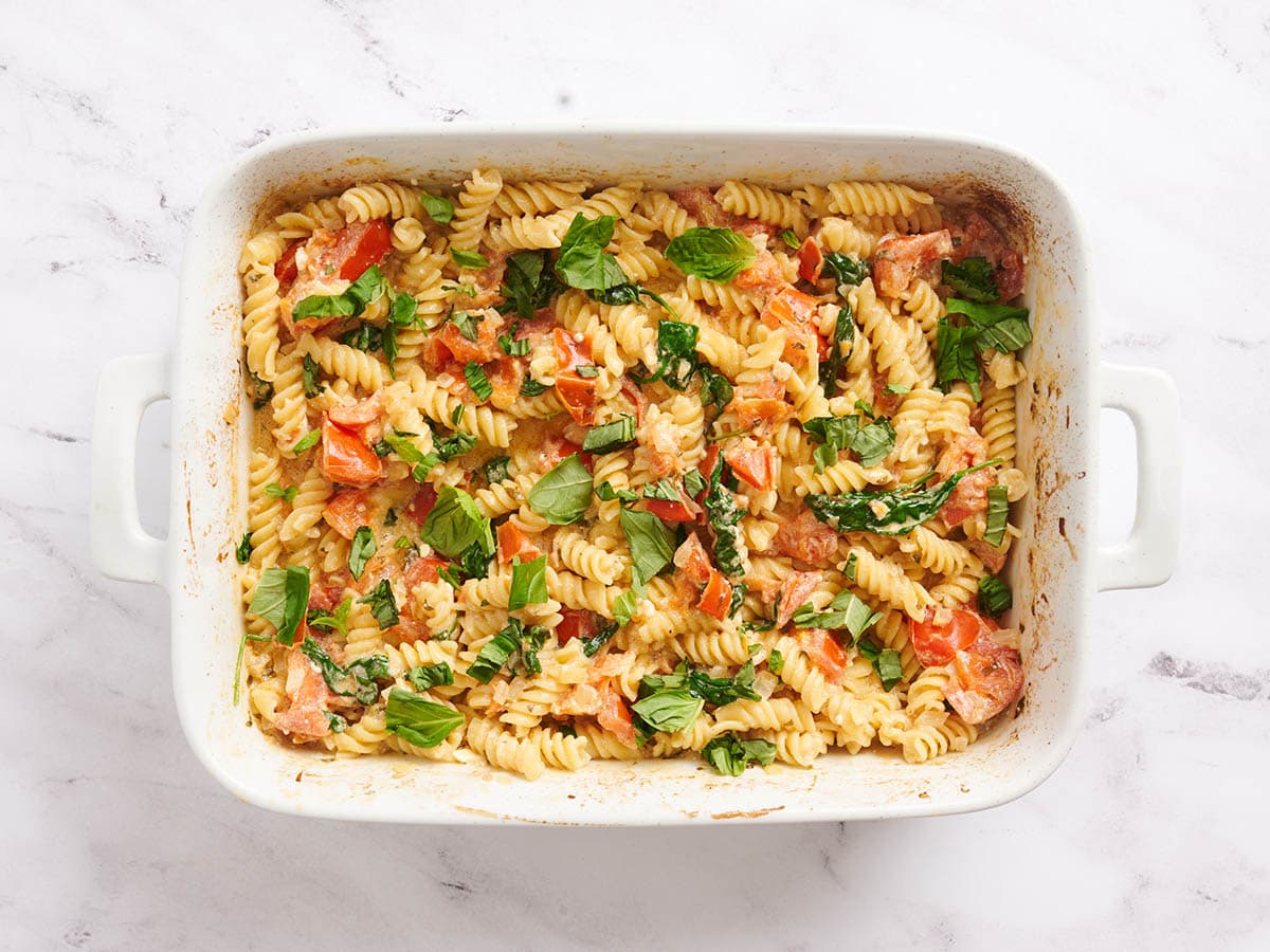 Pâtes feta cuites au four dans un plat allant au four garni de basilic.