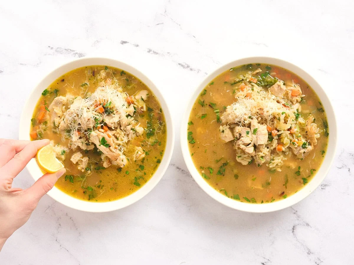 Deux bols de bouillon de riz avec une main pressant du citron sur un.