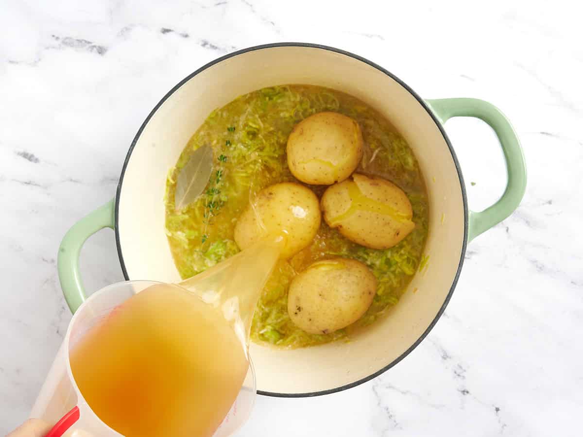 Bouillon versé sur des pommes de terre entières cuites dans une casserole.