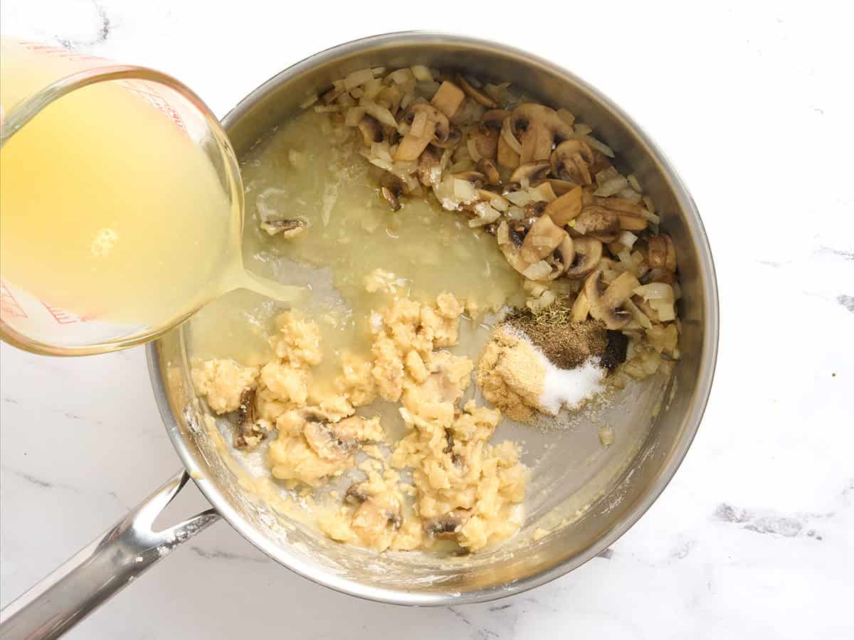 Bouillon ajouté à un roux et champignons dans une poêle.