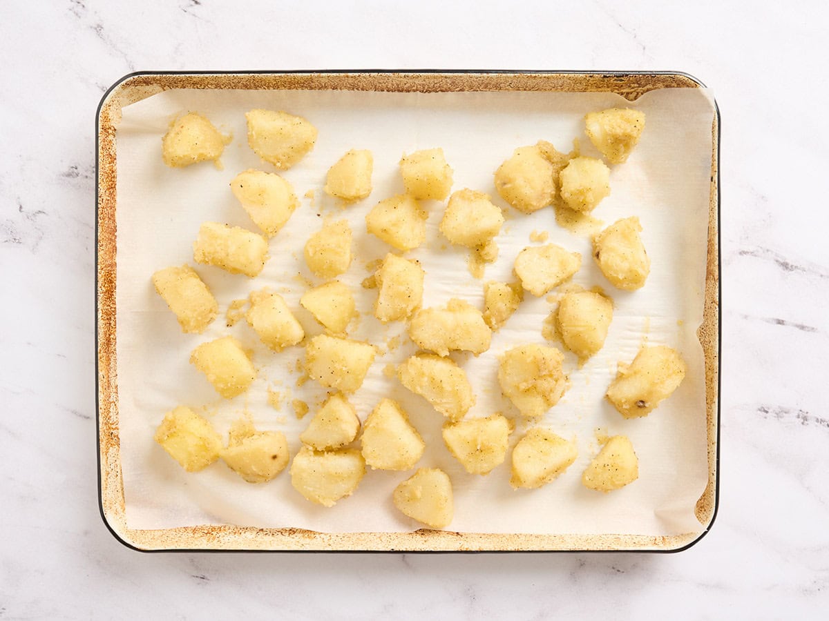 Pommes de terre sur une plaque à pâtisserie tapissée de papier sulfurisé.