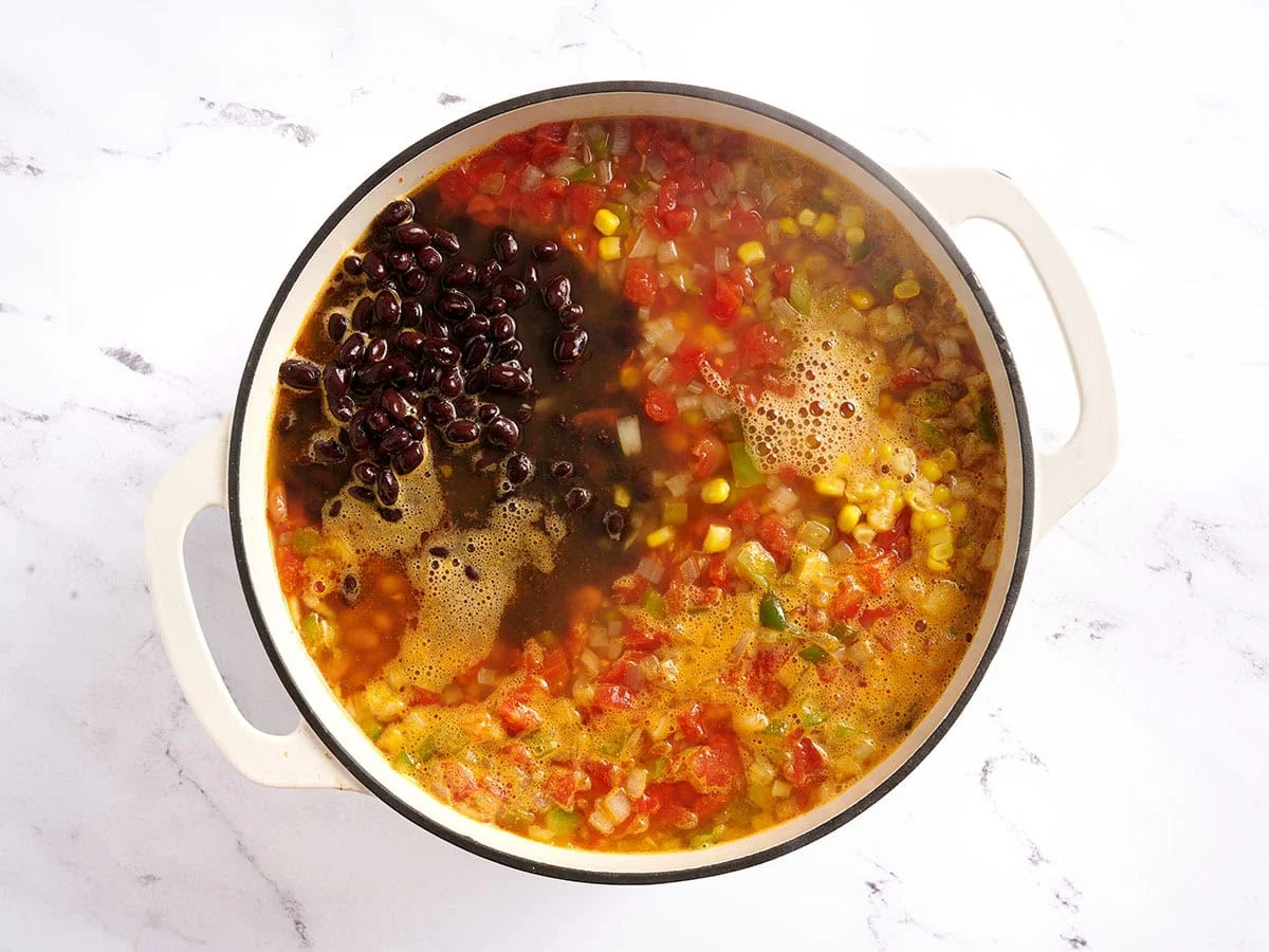 Maïs et haricots en conserve ajoutés à un pot de soupe tacos au poulet.