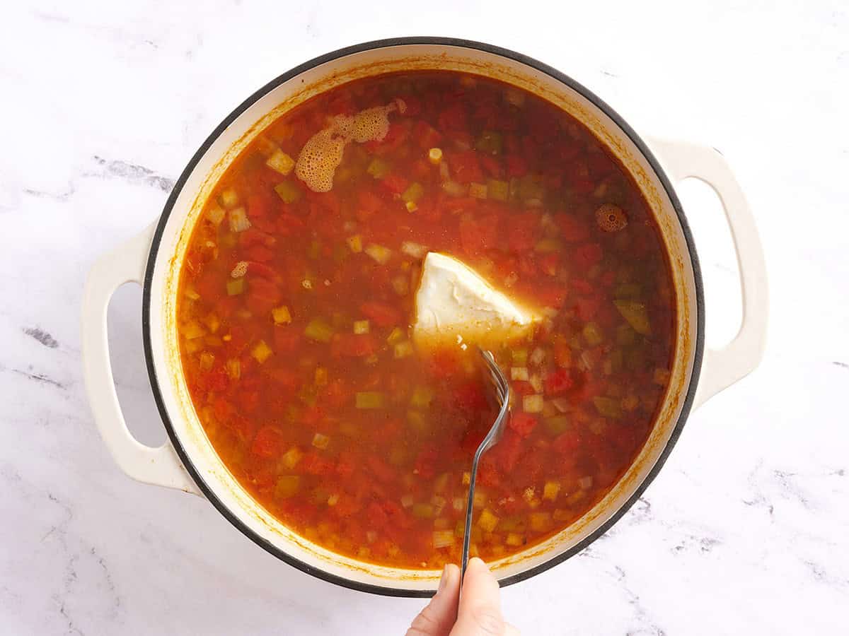 Une fourchette ajoutant du fromage à la crème à un pot de soupe tacos au poulet.