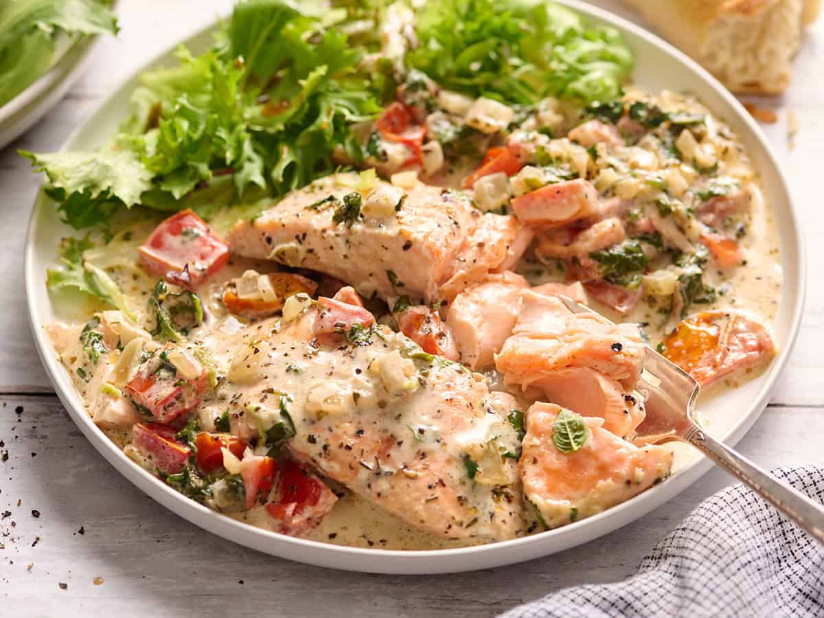 Vue latérale du saumon toscan sur une assiette avec salade.