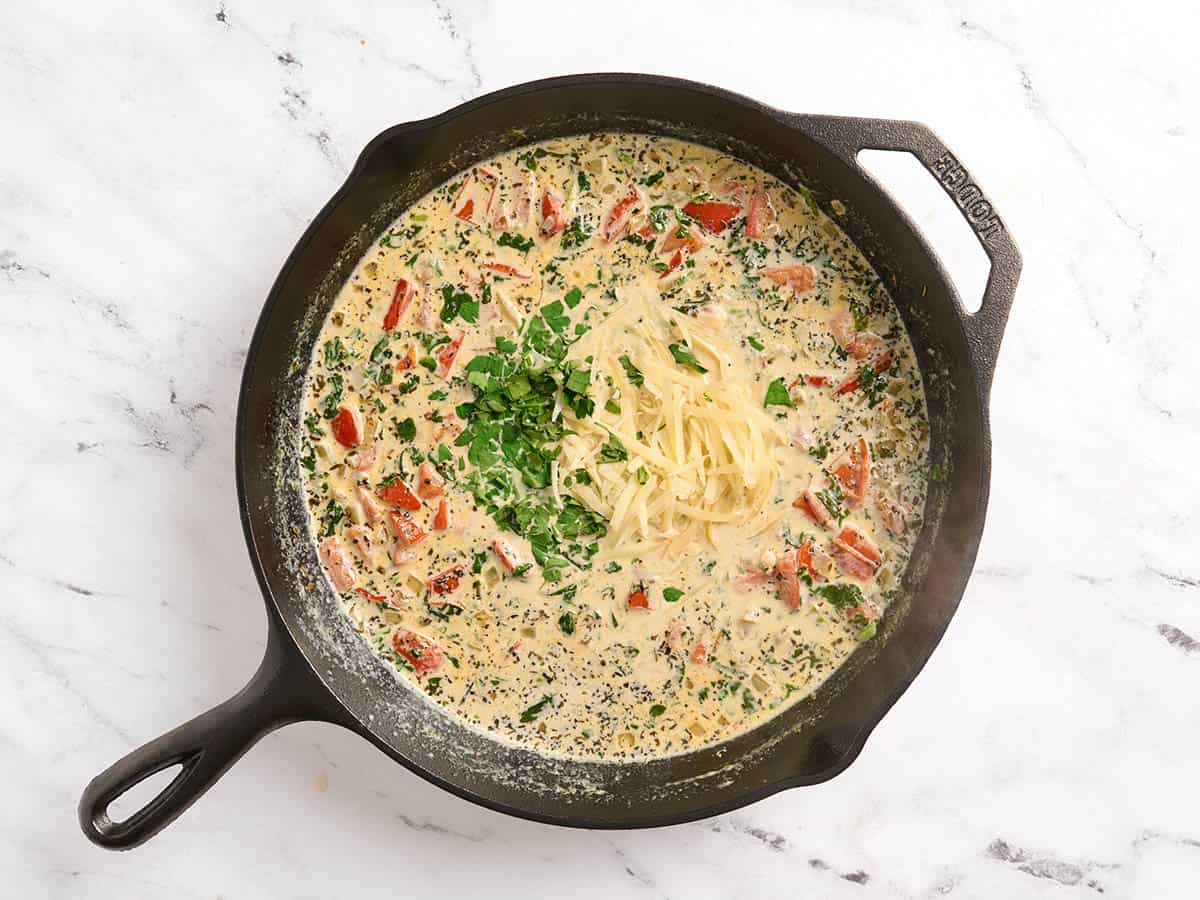 Persil et parmesan ajoutés à une poêle à saumon toscane.